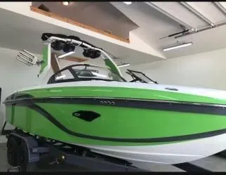 Slide: The Image of 2018 Centurion Ri217 boat in vibrant green, parked indoors on a trailer. - 4