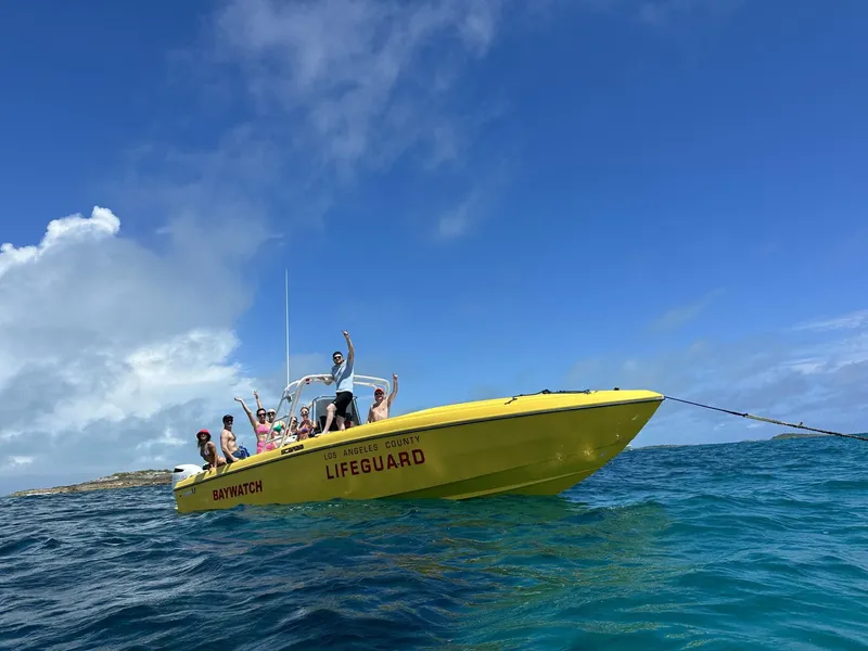 Slide: The Image of Yellow 1988 Wellcraft SCARAB SPORT lifeguard boat on ocean with people waving. - 0