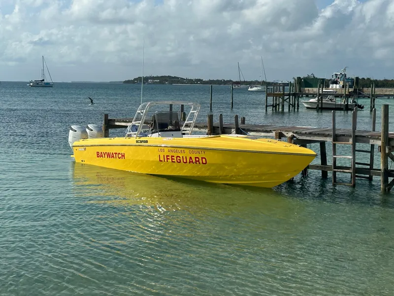 Slide: The Image of Bright yellow 1988 Wellcraft SCARAB SPORT lifeguard boat docked by the shore. - 1