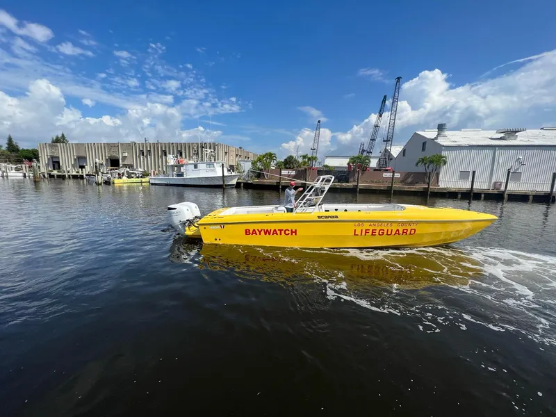 Slide: The Image of 1988 Wellcraft SCARAB SPORT lifeguard boat on water, sunny day, industrial background. - 2