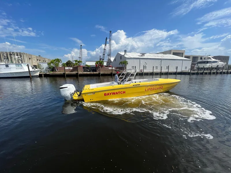 Slide: The Image of Yellow 1988 Wellcraft SCARAB SPORT boat labeled "Baywatch" on the water near a marina. - 3
