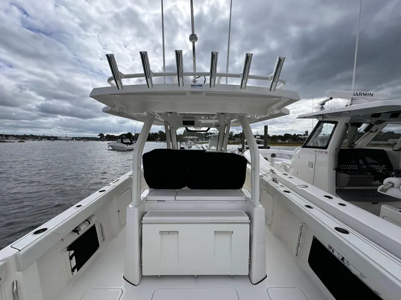 Slide: The Image of 2023 Pursuit S 328 Sport boat interior with seating and rod holders on a cloudy day. - 12