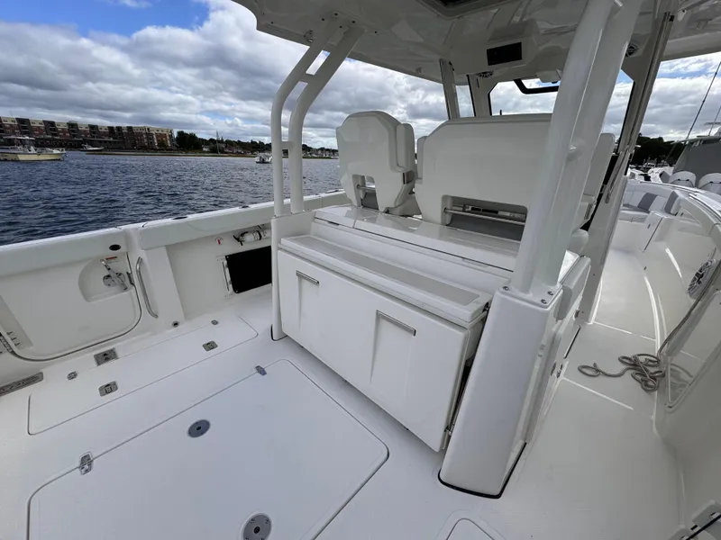 Slide: The Image of 2023 Pursuit S 328 Sport boat interior with seating and storage, docked by the water. - 17