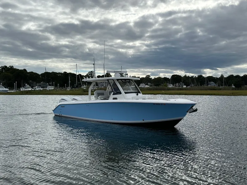 Slide: The Image of 2023 Pursuit S 328 Sport boat on calm water under cloudy sky. - 2
