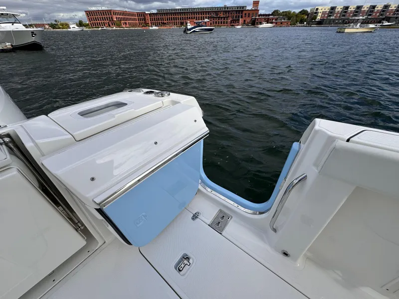 Slide: The Image of 2023 Pursuit S 328 Sport boat with open deck hatch, docked near waterfront buildings. - 22