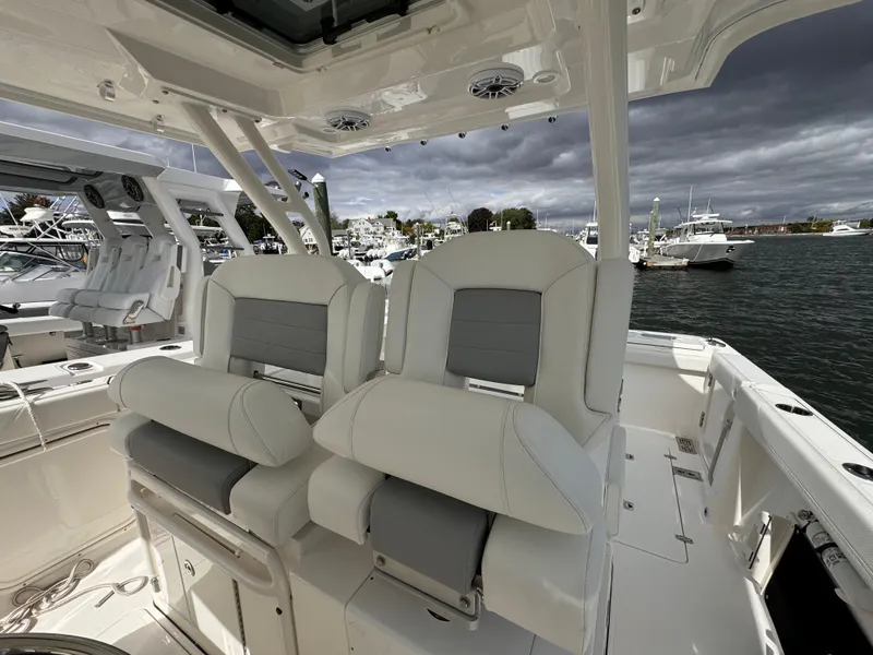 Slide: The Image of 2023 Pursuit S 328 Sport boat interior with plush seating, docked in a marina. - 27