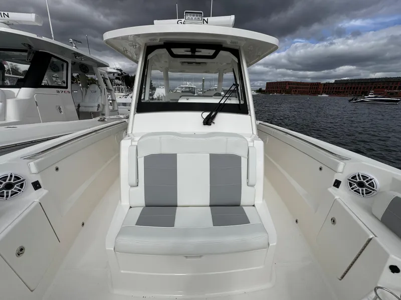 Slide: The Image of 2023 Pursuit S 328 Sport boat interior with seating, docked under cloudy skies. - 40