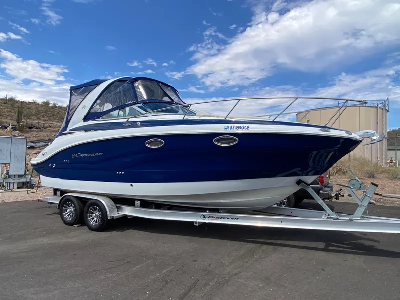 Slide: The Image of 2022 Crownline 264 CR boat on trailer, blue and white design, parked outdoors. - 2