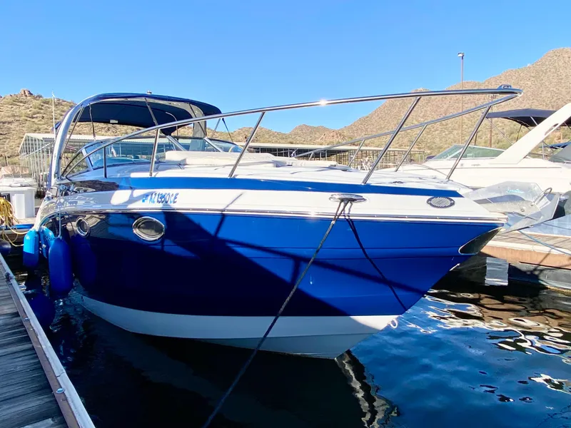 Slide: The Image of 2022 Crownline 264 CR boat docked in a marina, blue and white exterior. - 27