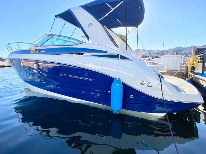 Slide: The Image of 2022 Crownline 264 CR boat docked, featuring sleek blue and white design. - 28