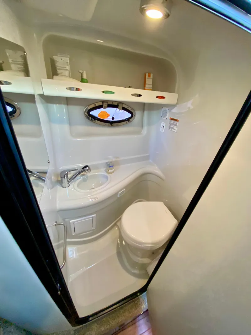 Slide: The Image of 2022 Crownline 264 CR boat bathroom with sink, toilet, and storage shelves. - 36
