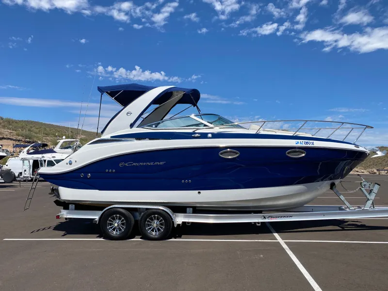 Slide: The Image of 2022 Crownline 264 CR boat on trailer under blue sky. - 4