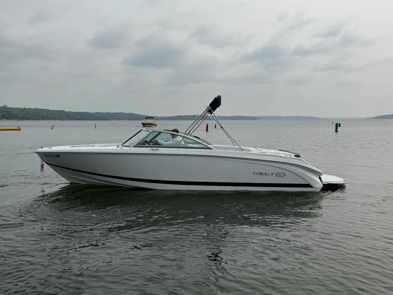 Slide: The Image of 2023 Cobalt 220S boat on calm lake under cloudy sky. - 1