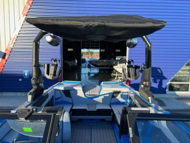 Slide: The Image of 2023 Nautique S23 boat with blue accents and canopy, docked near a blue building. - 10
