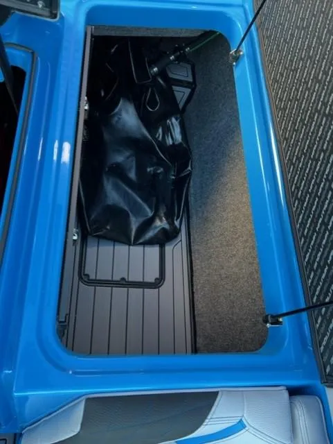 Slide: The Image of 2023 Nautique S23 storage compartment with blue trim and black interior. - 17