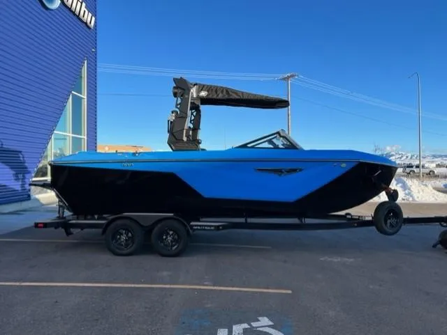Slide: The Image of 2023 Nautique S23 boat in blue and black on a trailer, parked outdoors. - 7