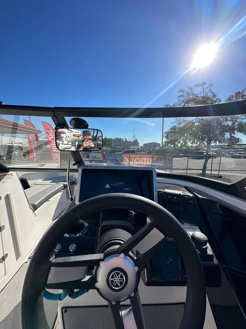Slide: The Image of 2023 Yamaha AR250 jet boat cockpit with steering wheel and dashboard under bright sun. - 16