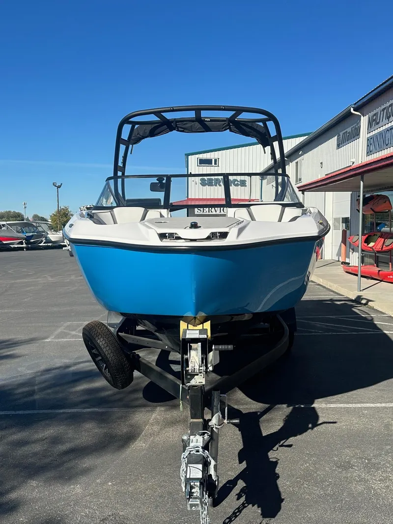 Slide: The Image of 2023 Yamaha AR250 jet boat in blue, parked on a trailer at a dealership. - 4