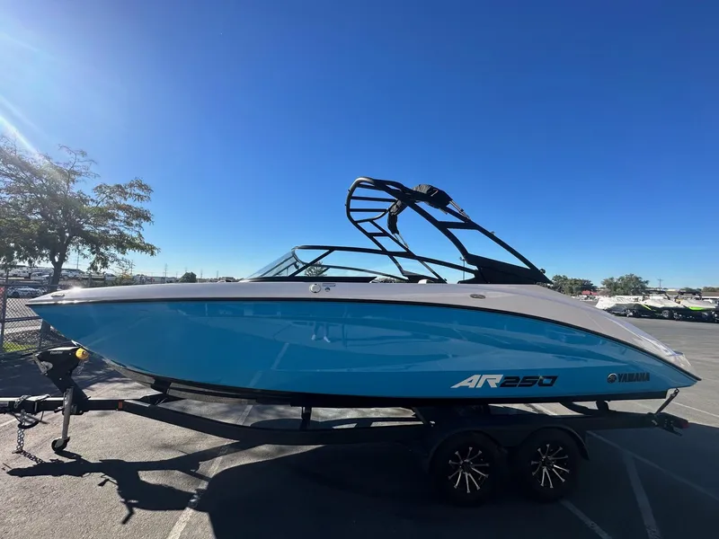 Slide: The Image of 2023 Yamaha AR250 jet boat on trailer, blue and white design, parked outdoors. - 6