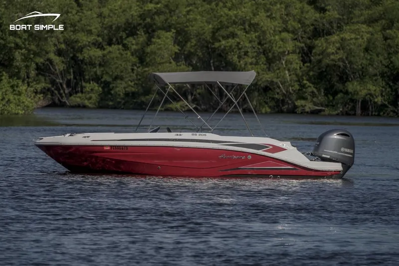 Slide: The Image of 2023 Hurricane SunDeck Sport 205 OB boat on a calm lake with lush green trees. - 3