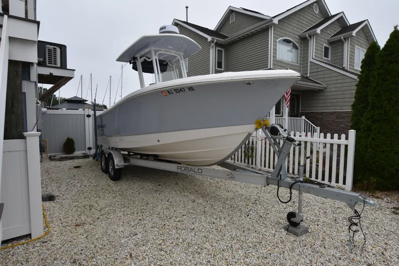 The Image of 2023 Robalo R230 Center Console boat on trailer in residential driveway. - 0