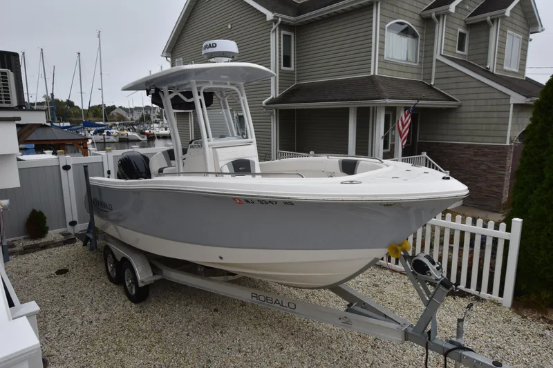Slide: The Image of 2023 Robalo R230 Center Console boat on trailer in residential driveway. - 10