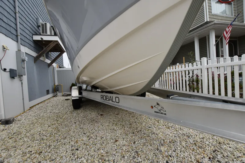 Slide: The Image of 2023 Robalo R230 Center Console boat on trailer, parked beside a house. - 13