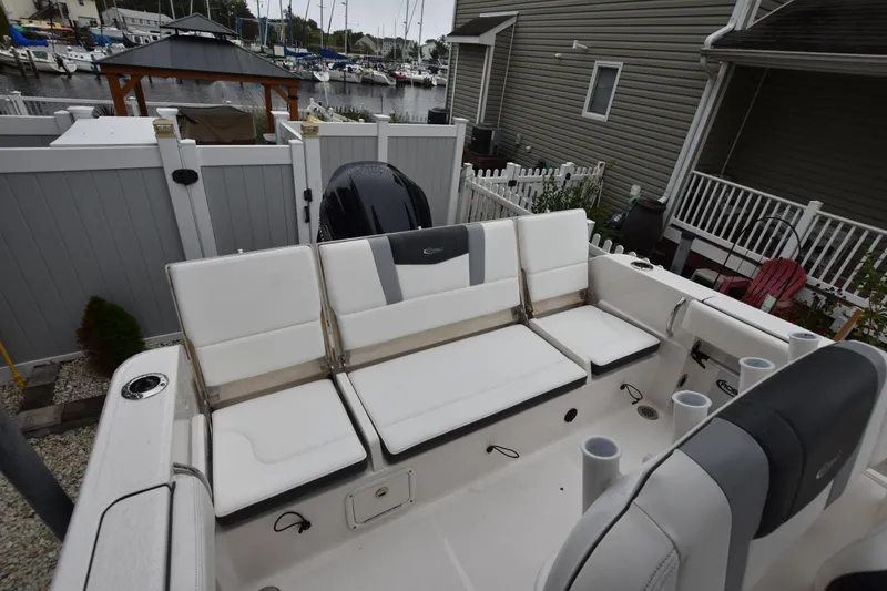 Slide: The Image of 2023 Robalo R230 Center Console boat with white seating, docked near a marina. - 18