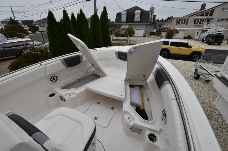 Slide: The Image of 2023 Robalo R230 Center Console boat with open storage compartments in a residential driveway. - 27