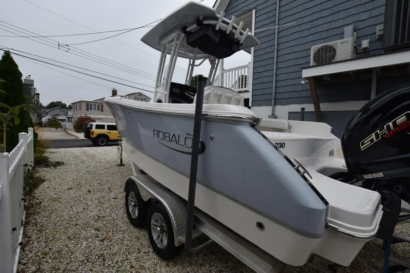 Slide: The Image of 2023 Robalo R230 Center Console boat on trailer, parked in residential area. - 4