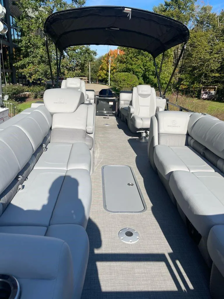 Slide: The Image of 2024 Regency 250 LE3 pontoon boat with spacious seating and canopy, set in a sunny outdoor location. - 4
