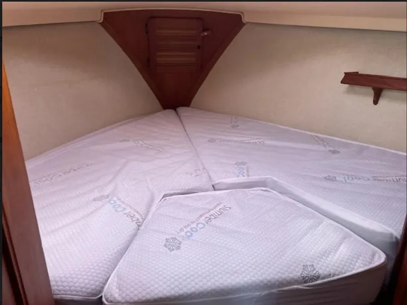 Slide: The Image of 1987 Island Packet 31 sailboat cabin with V-berth and white bedding. - 15