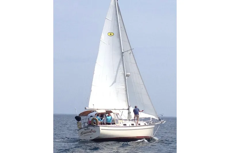 Slide: The Image of 1987 Island Packet 31 sailboat cruising on open water with full sails. - 17