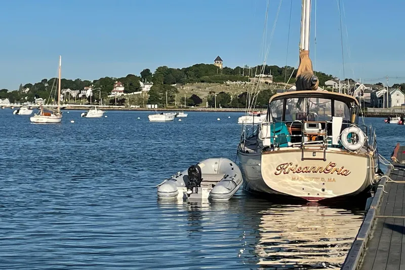 Slide: The Image of 1987 Island Packet 31 sailboat docked in a scenic harbor with surrounding boats. - 18