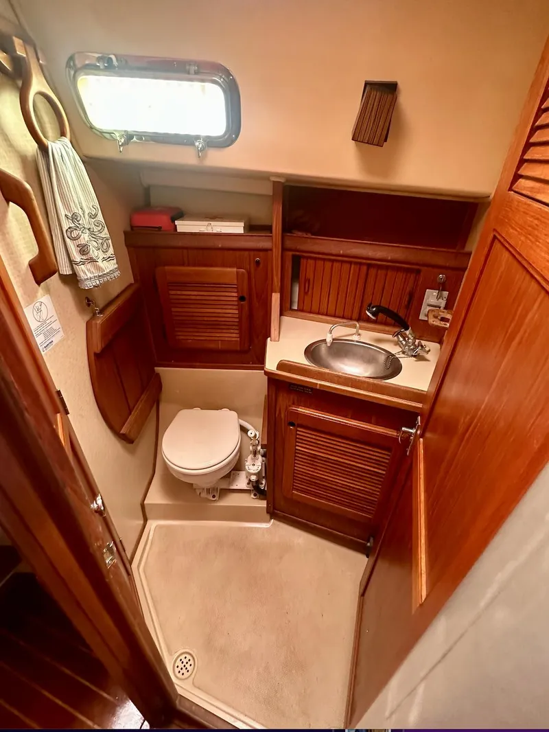 Slide: The Image of 1987 Island Packet 31 sailboat bathroom with wooden cabinetry and compact design. - 9