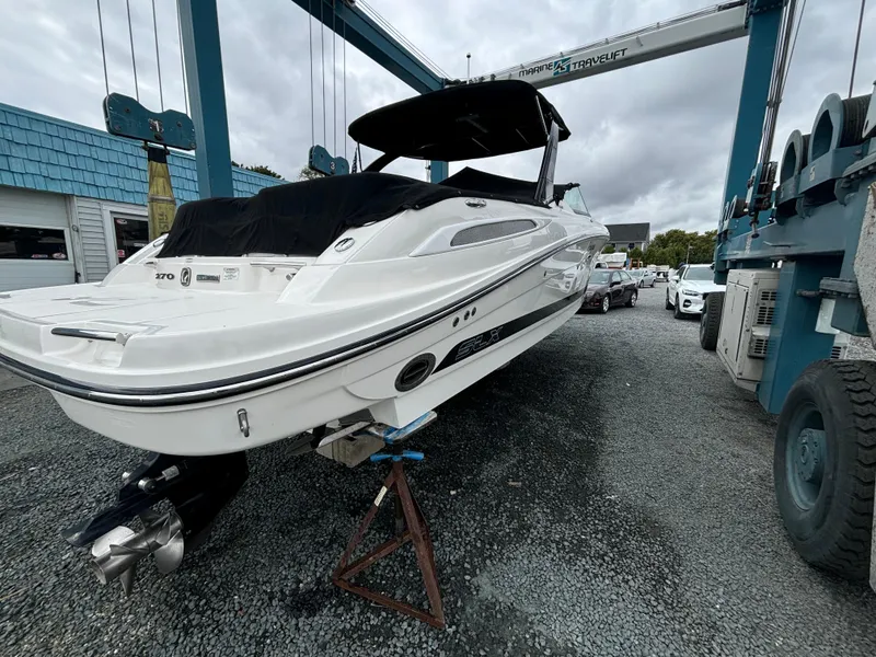 Slide: The Image of 2013 Sea Ray 270 SLX boat on dry dock, white exterior, covered cockpit. - 6