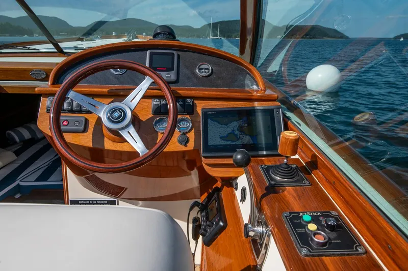 Slide: The Image of 2004 Hinckley Talaria 29 Runabout dashboard with wooden steering wheel and navigation controls. - 18