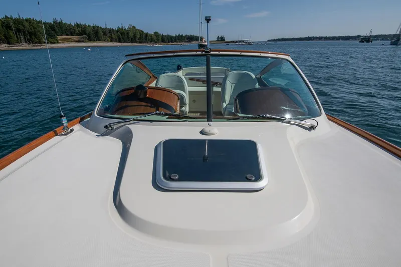 Slide: The Image of 2004 Hinckley Talaria 29 Runabout on calm water, showcasing sleek design and windshield. - 31