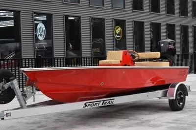 Slide: The Image of Red 2023 ZCB Curlew 18 boat on Sport Trail trailer, parked outside a building. - 0