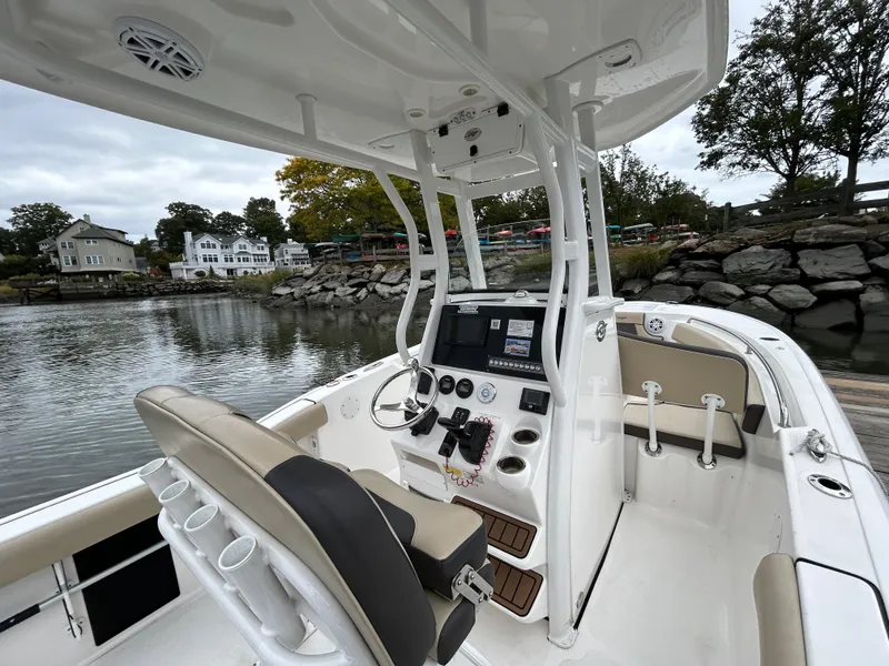 Slide: The Image of 2021 Tidewater 232 LXF boat interior with helm, docked by a scenic waterfront. - 13