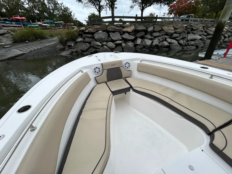 Slide: The Image of 2021 Tidewater 232 LXF boat with beige seating, docked near rocky shoreline. - 3