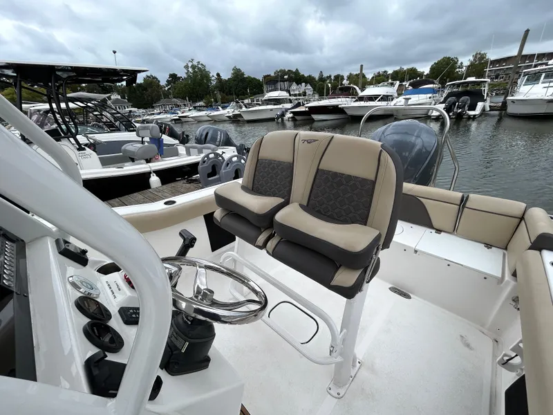 Slide: The Image of 2021 Tidewater 232 LXF boat interior with dual seats and steering wheel at marina. - 9