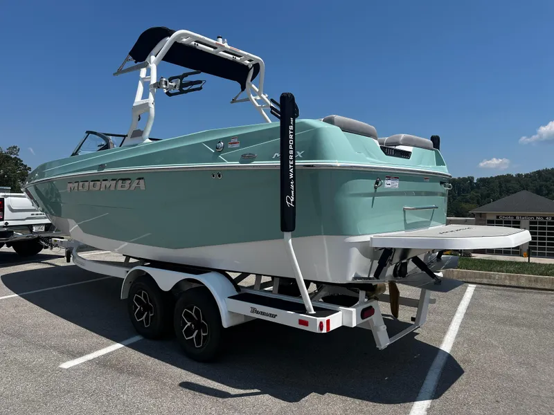 Slide: The Image of 2025 Moomba Max boat on trailer in parking lot, sunny day. - 2