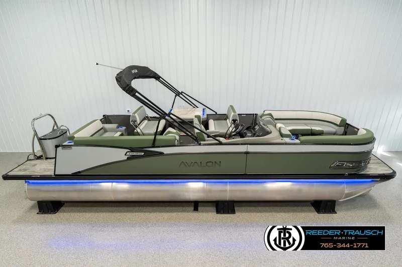 Slide: The Image of 2025 Avalon Catalina Entertainer pontoon boat with green seating and sleek design in showroom. - 0