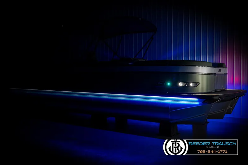 Slide: The Image of 2025 Avalon Catalina Entertainer pontoon boat with blue LED lights in a dimly lit setting. - 3