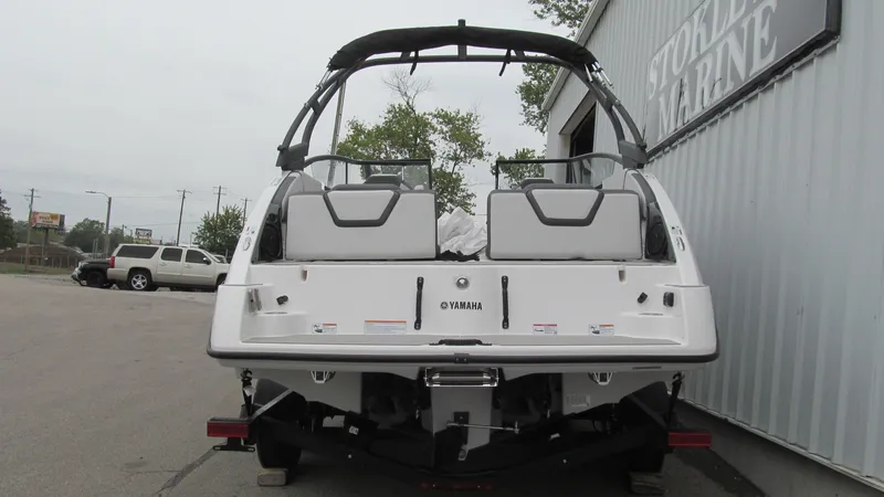 Slide: The Image of 2025 Yamaha Boats AR250, rear view, parked near a marine building. - 3