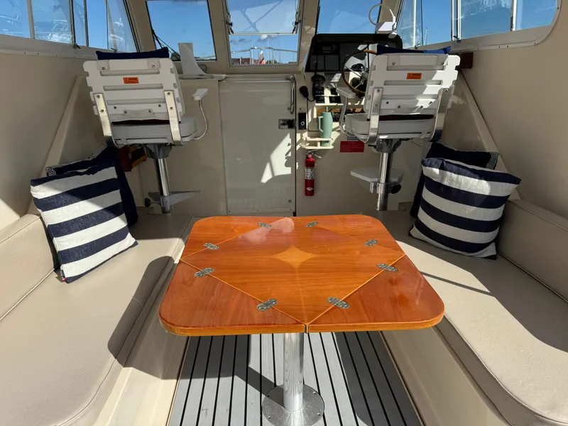 Slide: The Image of Interior of 2004 Mainship 30 Pilot II Express Cruiser with seating and wooden table. - 11