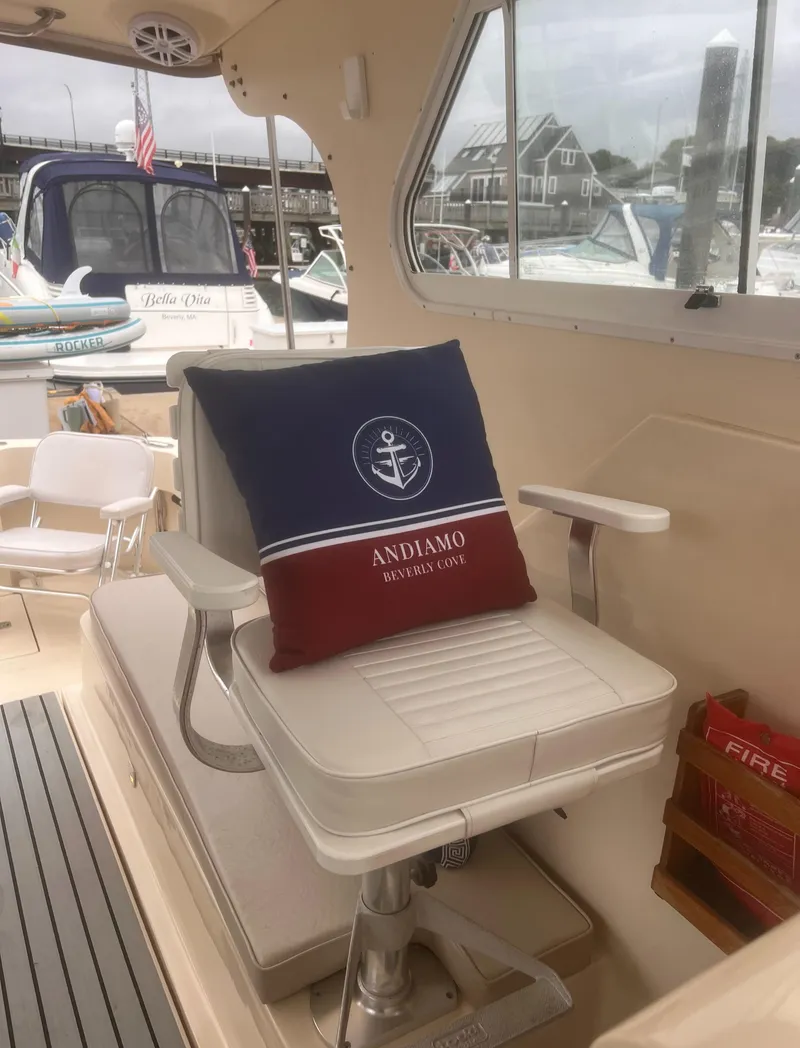 Slide: The Image of 2004 Mainship 30 Pilot II Express Cruiser interior with cushioned seating and nautical-themed pillow. - 12
