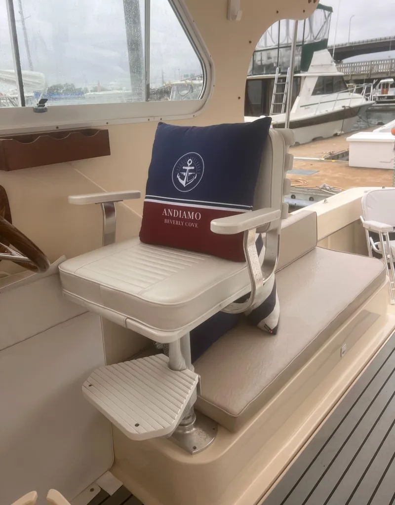 Slide: The Image of 2004 Mainship 30 Pilot II Express Cruiser interior with cushioned seating and nautical-themed pillow. - 13