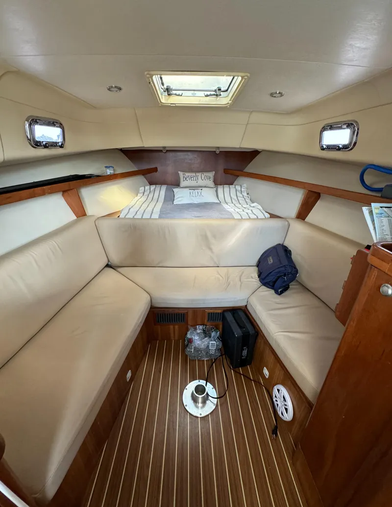 Slide: The Image of 2004 Mainship 30 Pilot II Express Cruiser cabin with beige seating and wood flooring. - 18